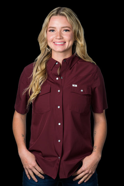 Woman wearing a maroon short-sleeve shirt with a brand logo on a black background